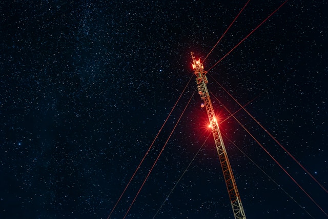 Cell tower at night held up by guy wires